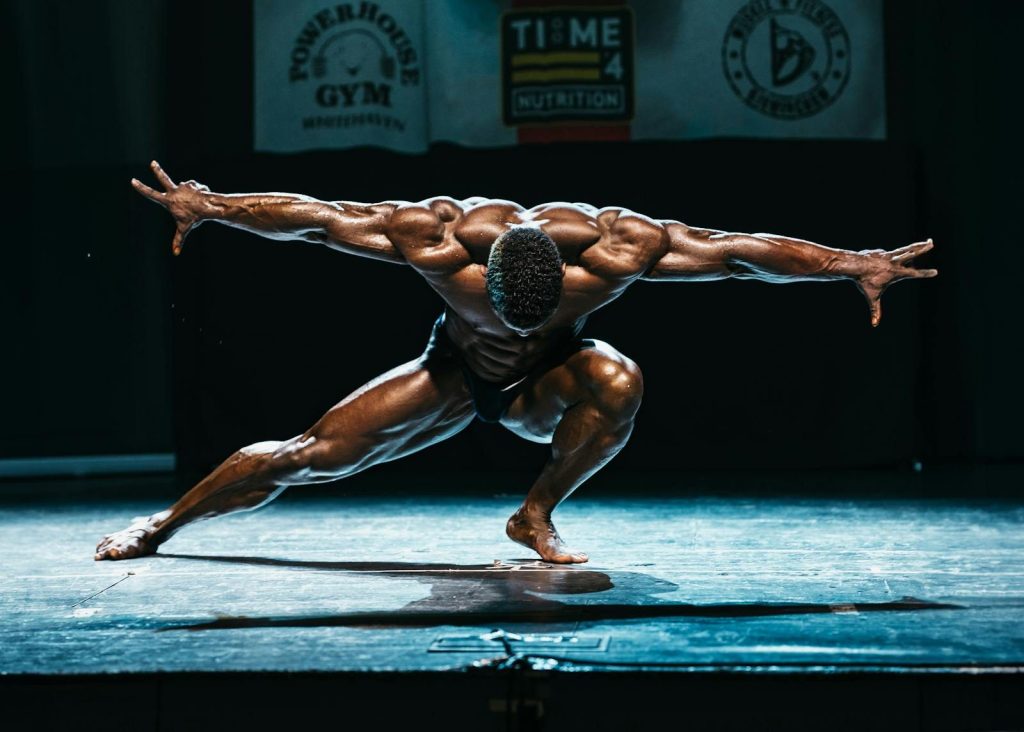 Powerful bodybuilder showcasing muscles in dramatic stage pose.